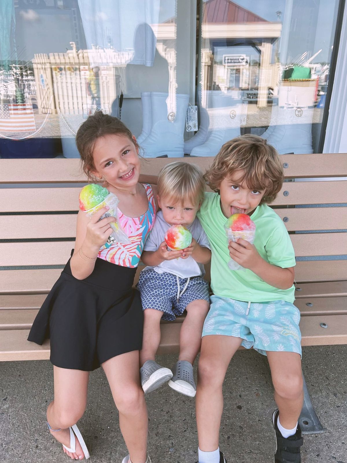 a group of children sitting on a bench eating ice cream